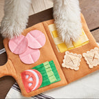 Dog playing with a toy shaped like a pizza on a wooden floor.