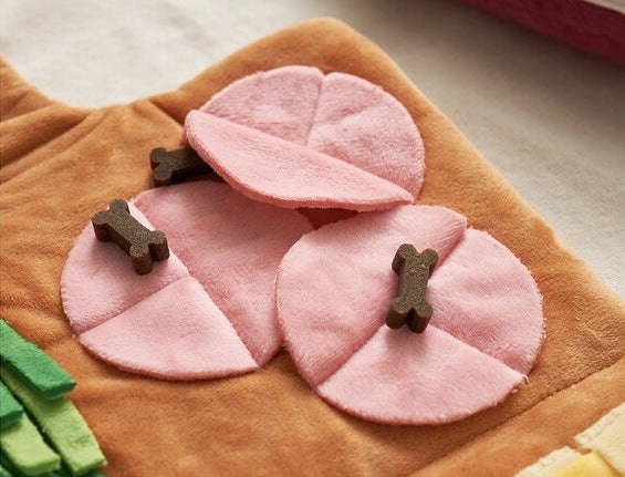 Pink pet toys with bone-shaped treats on a brown blanket