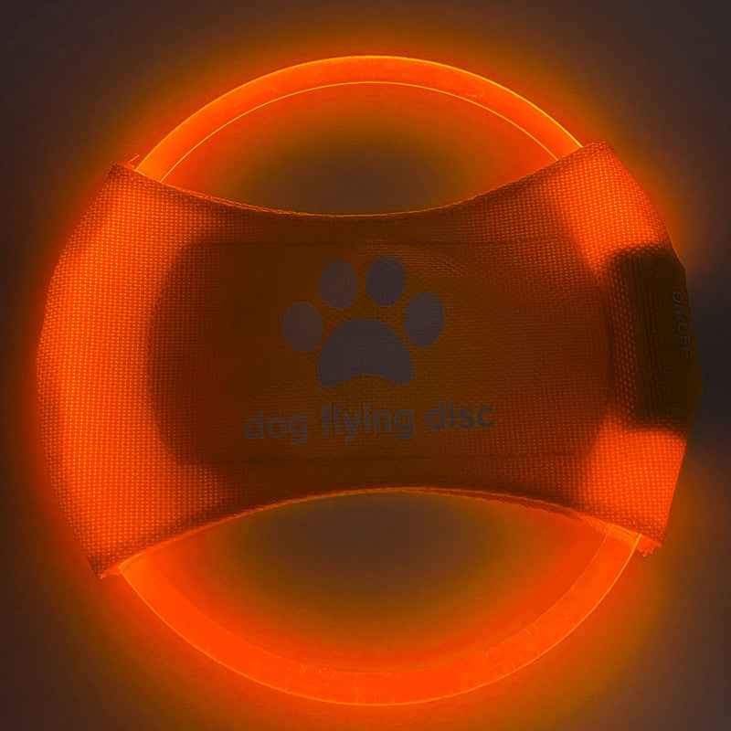 Orange dog flying disc with paw print design on a dark background