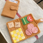 Felt play food set on a wooden surface with a napkin labeled 'menu'.