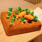 Plush carrot toys on a brown tray with green leaves on a wooden surface.
